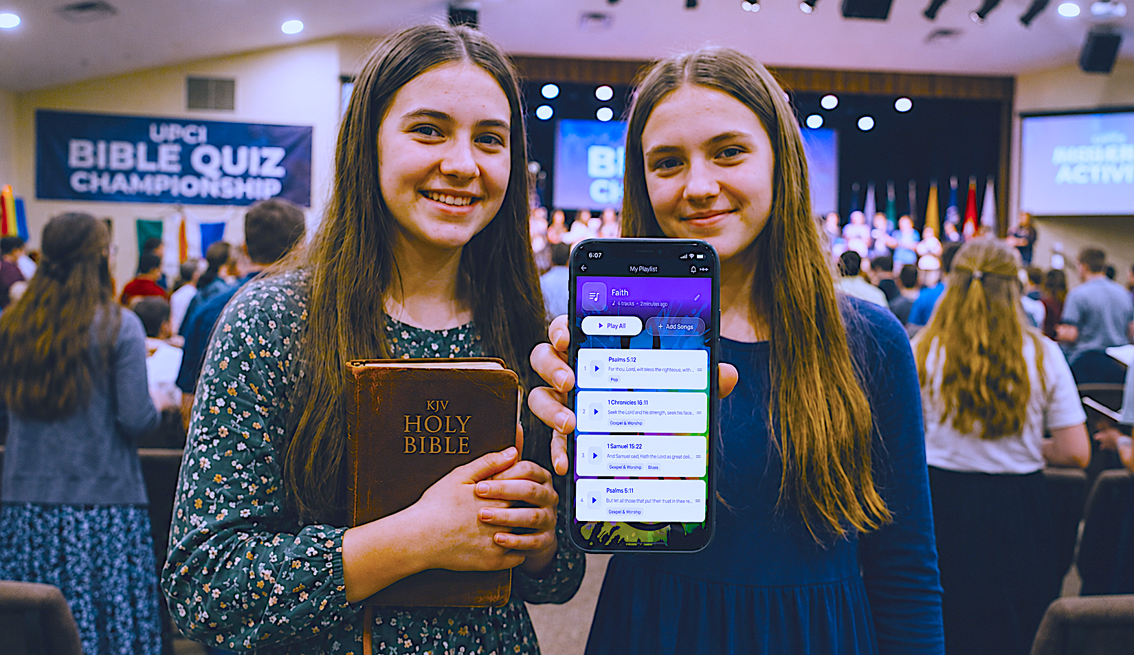Two teen Bible quizzers at the UPCI Bible Quiz Championship — one holds a KJV Holy Bible and the other shows a WordSong 'Faith' playlist with Psalms, 1 Chronicles, and 1 Samuel verses